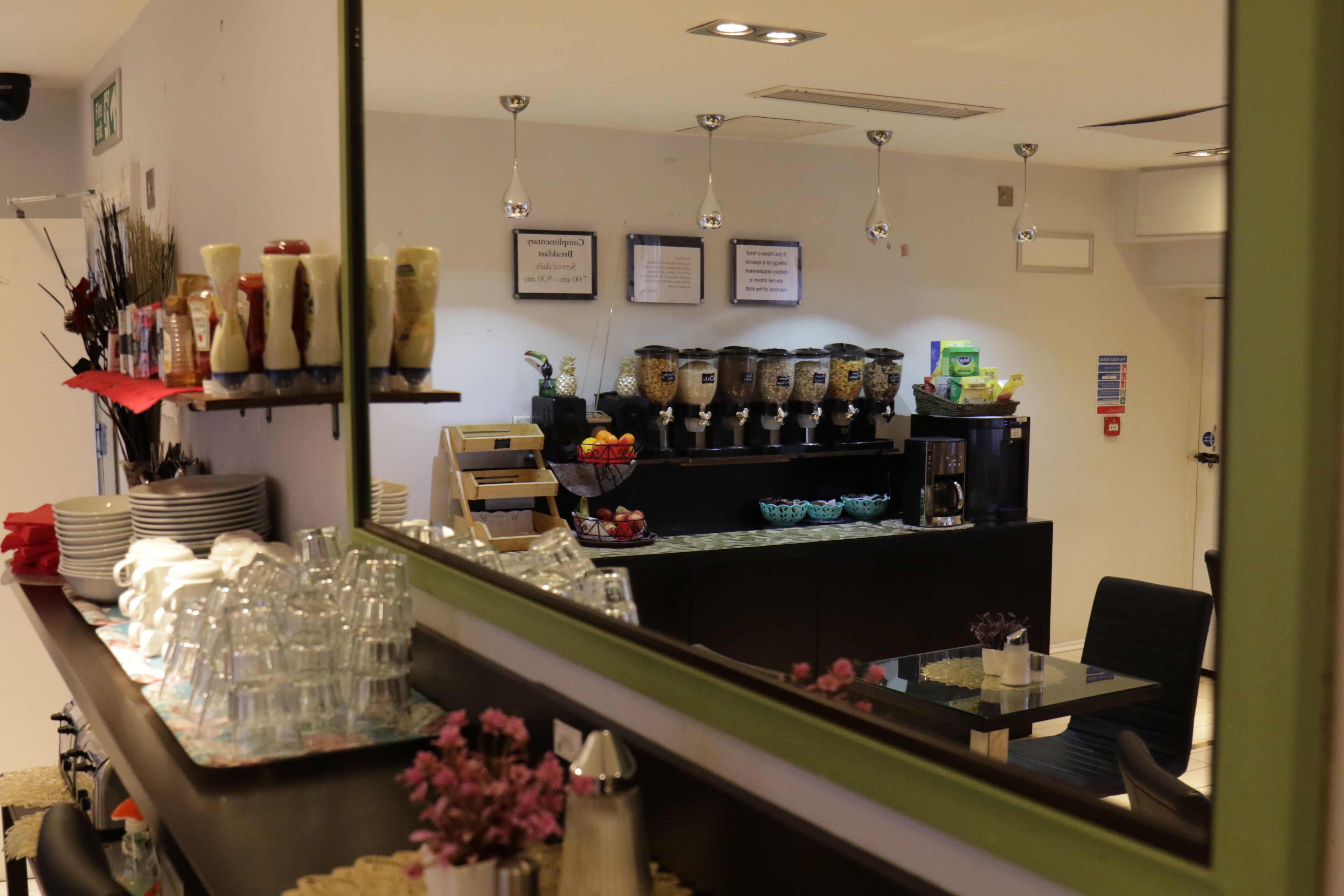 A hotel reception area with a counter, glassware, and food dispensers.