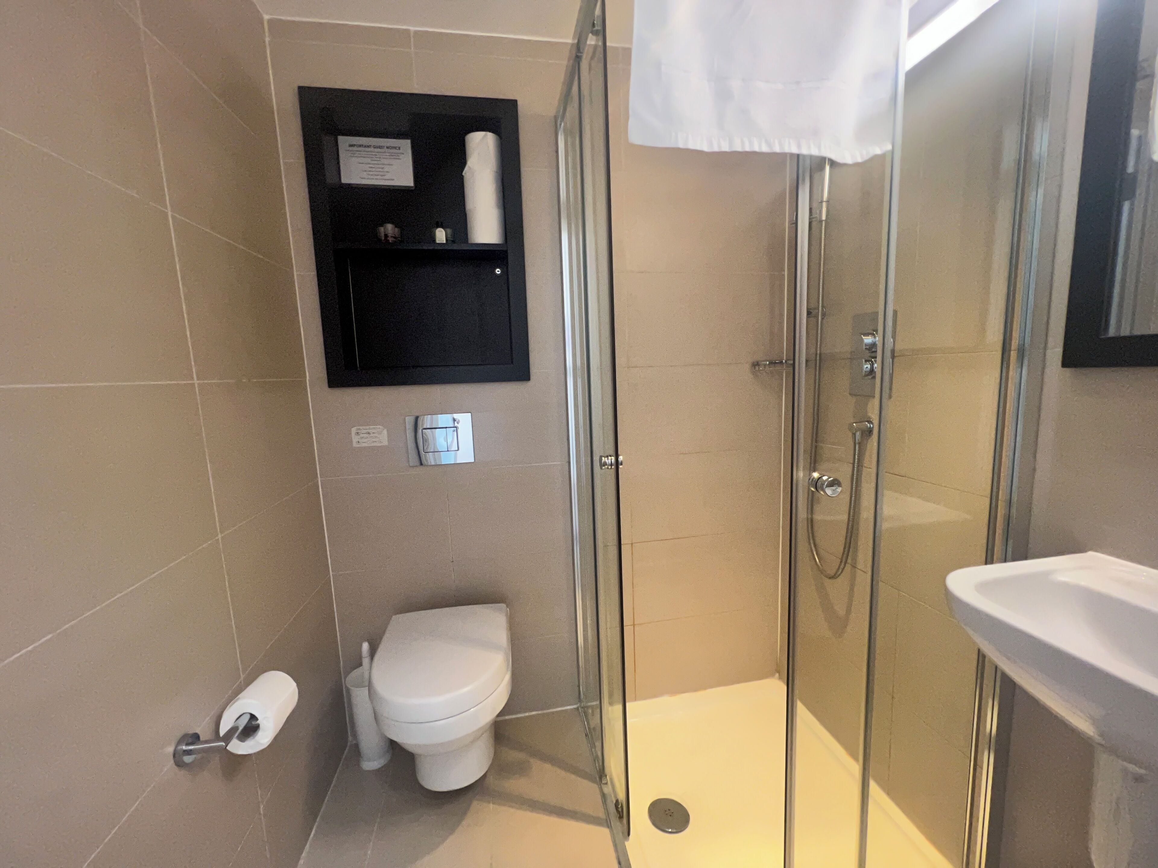 Une salle de bain comprenant des toilettes, une douche fermée par une paroi de verre et un lavabo.