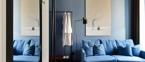 A modern living room with two blue sofas, a black floor lamp, and two abstract wall art pieces.