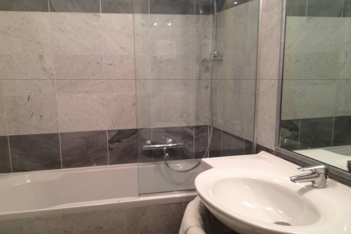 A bathroom with a bathtub, a shower, and a sink.