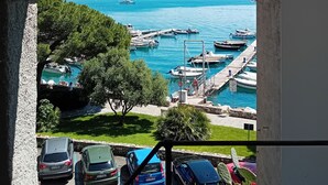 A view through an archway of a marina with boats docked, a clear blue sky, and mountains in the distance. - Hotel Paradiso (Portovenere)
