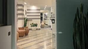 A modern hotel lobby with a marble floor, potted plants, and a reception desk. - Hotel Paradiso (Portovenere)