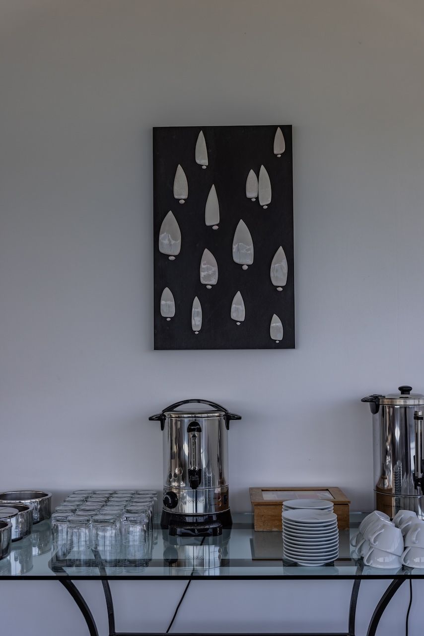 A kitchen counter with a coffee maker, a stack of plates, and a decorative wall piece.