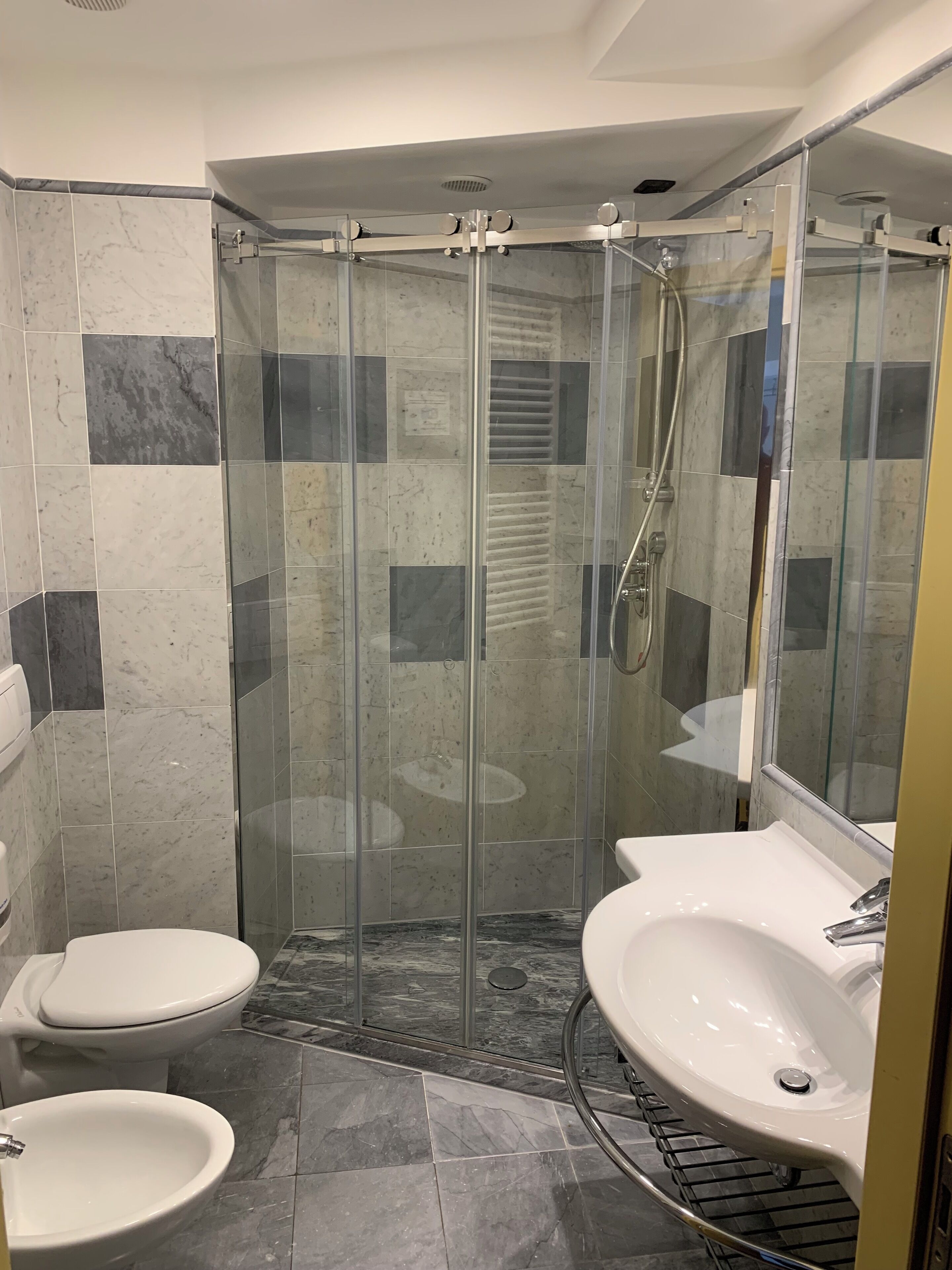 A modern bathroom with a glass-enclosed shower, a toilet, and two sinks.