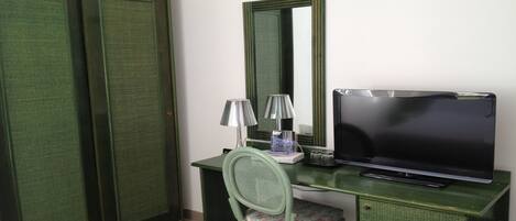 A room with a desk, a chair, a television, and a wardrobe.