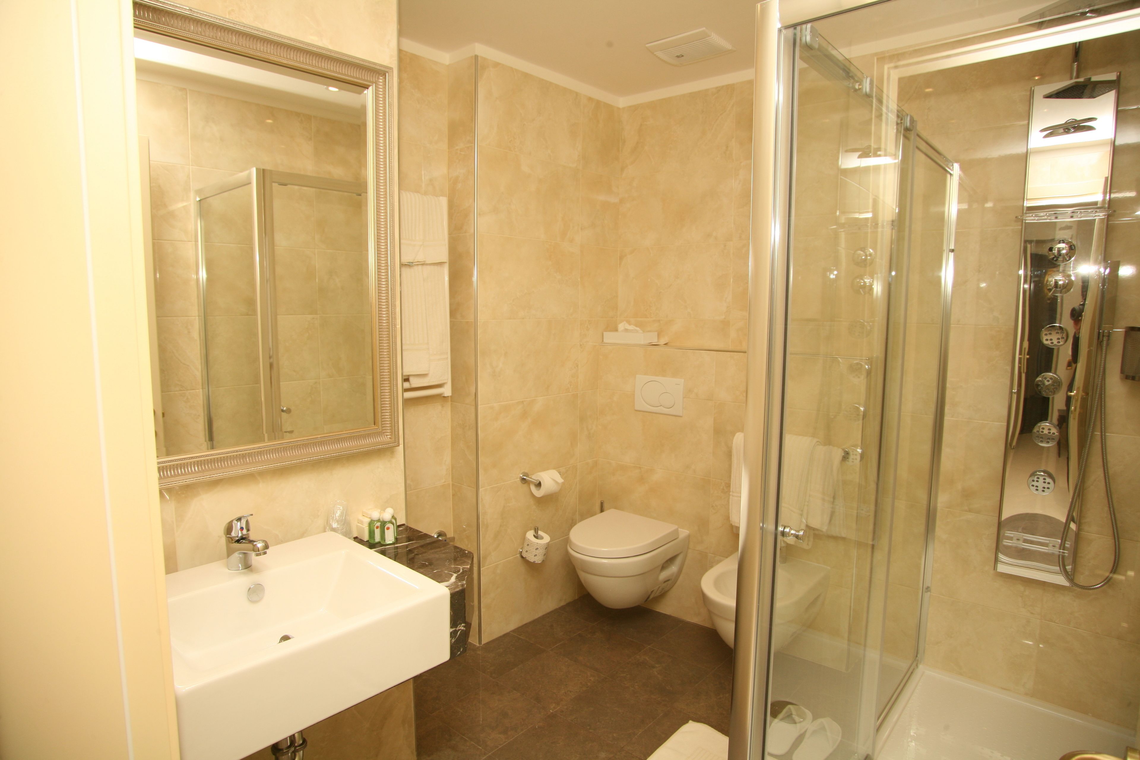 A modern bathroom with a glass-enclosed shower, a white sink, and a toilet.