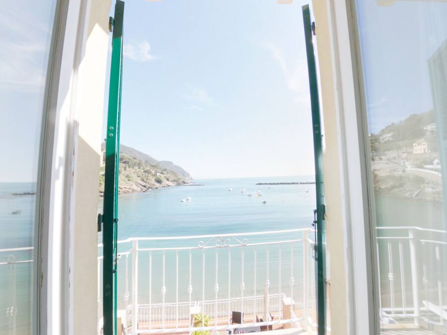 Un balcon offrant une vue sur une zone côtière, notamment un littoral rocheux et une mer calme.