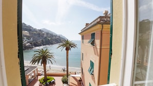 A balcony with a view of a beach, palm trees, and coastal buildings.