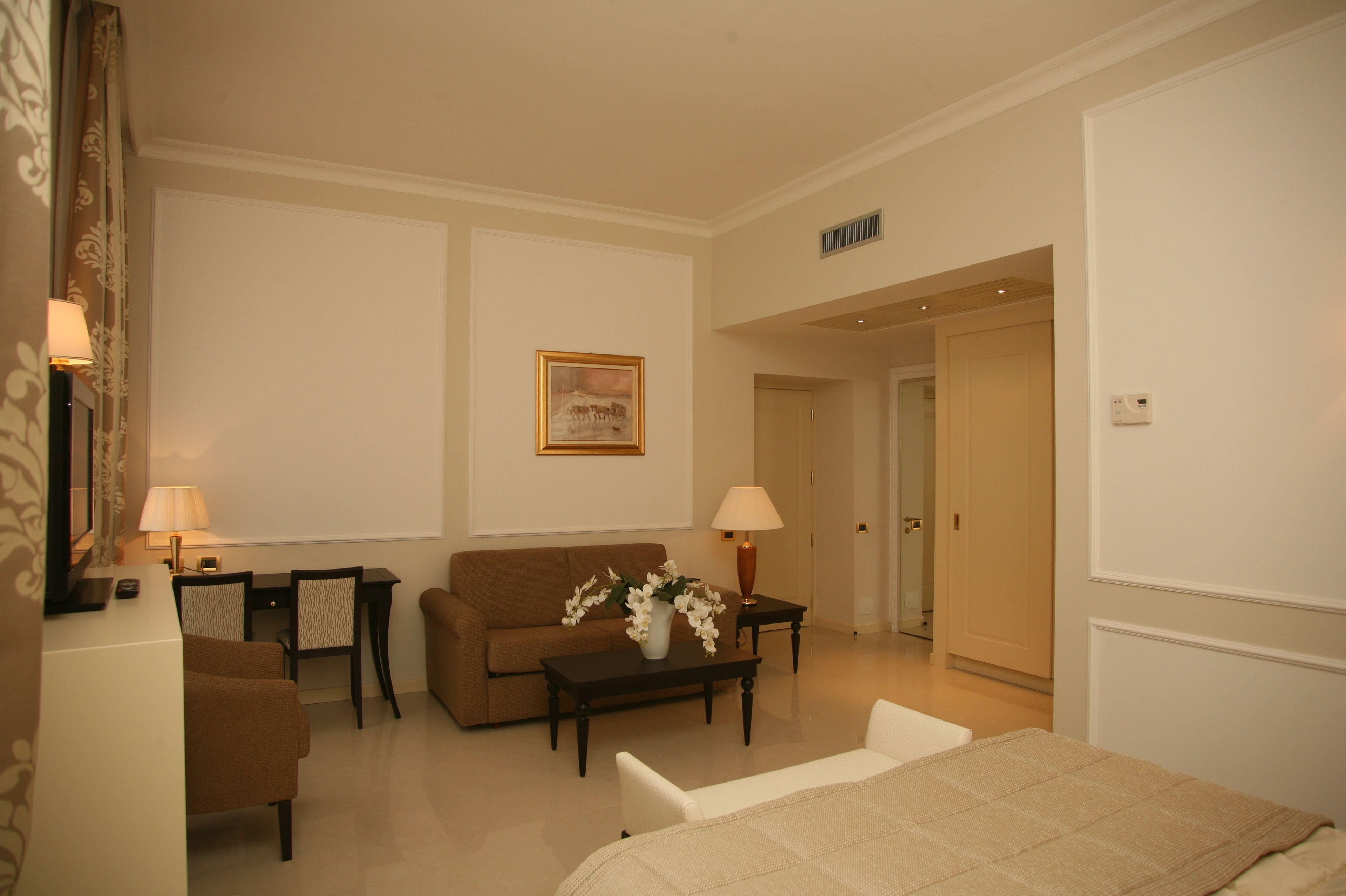 A hotel room with a sofa, two armchairs, a coffee table, and a TV.