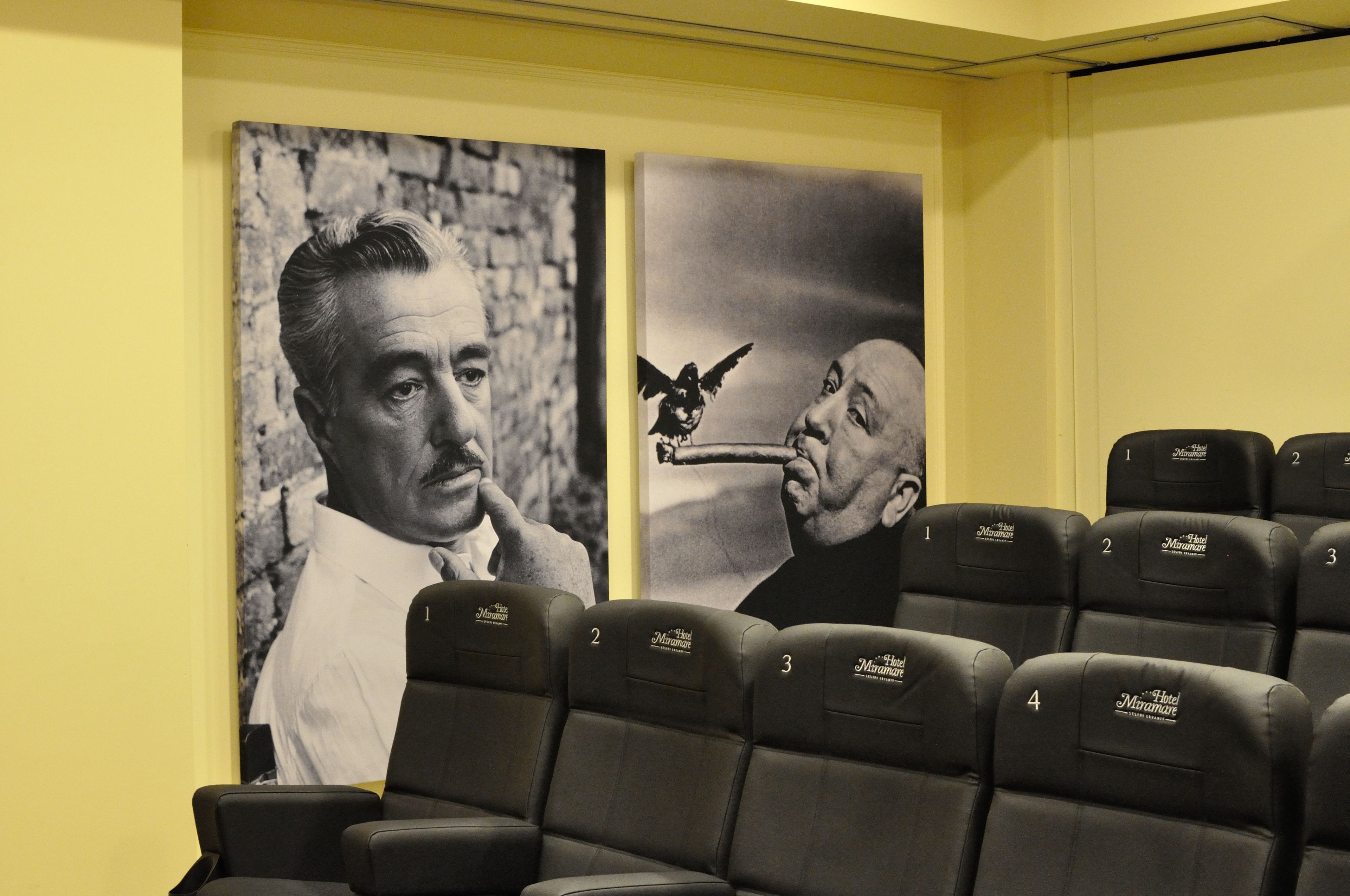A cinema room with black leather seats and two black-and-white movie posters on the wall.