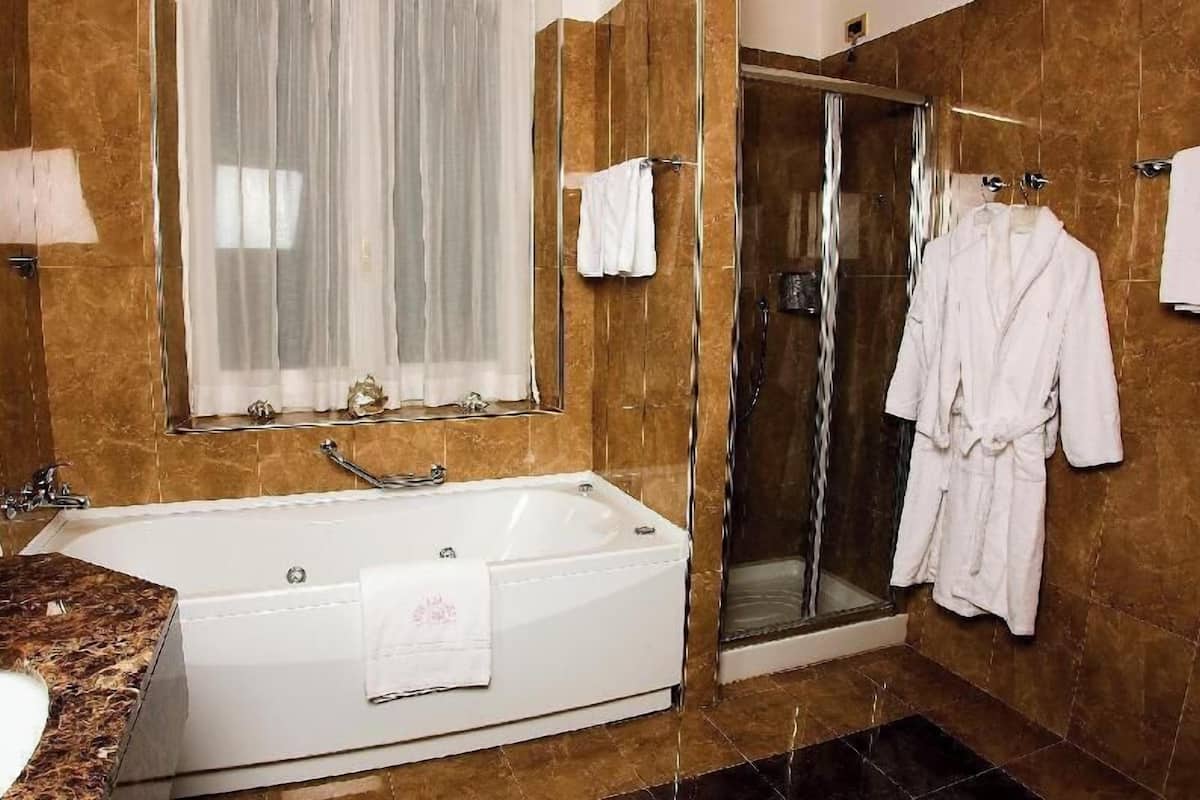 Een badkamer met een bad, een douchecabine van glas en een badjas hangend aan de muur.