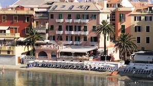 A coastal hotel with multiple balconies, a beachside bar, and a restaurant.