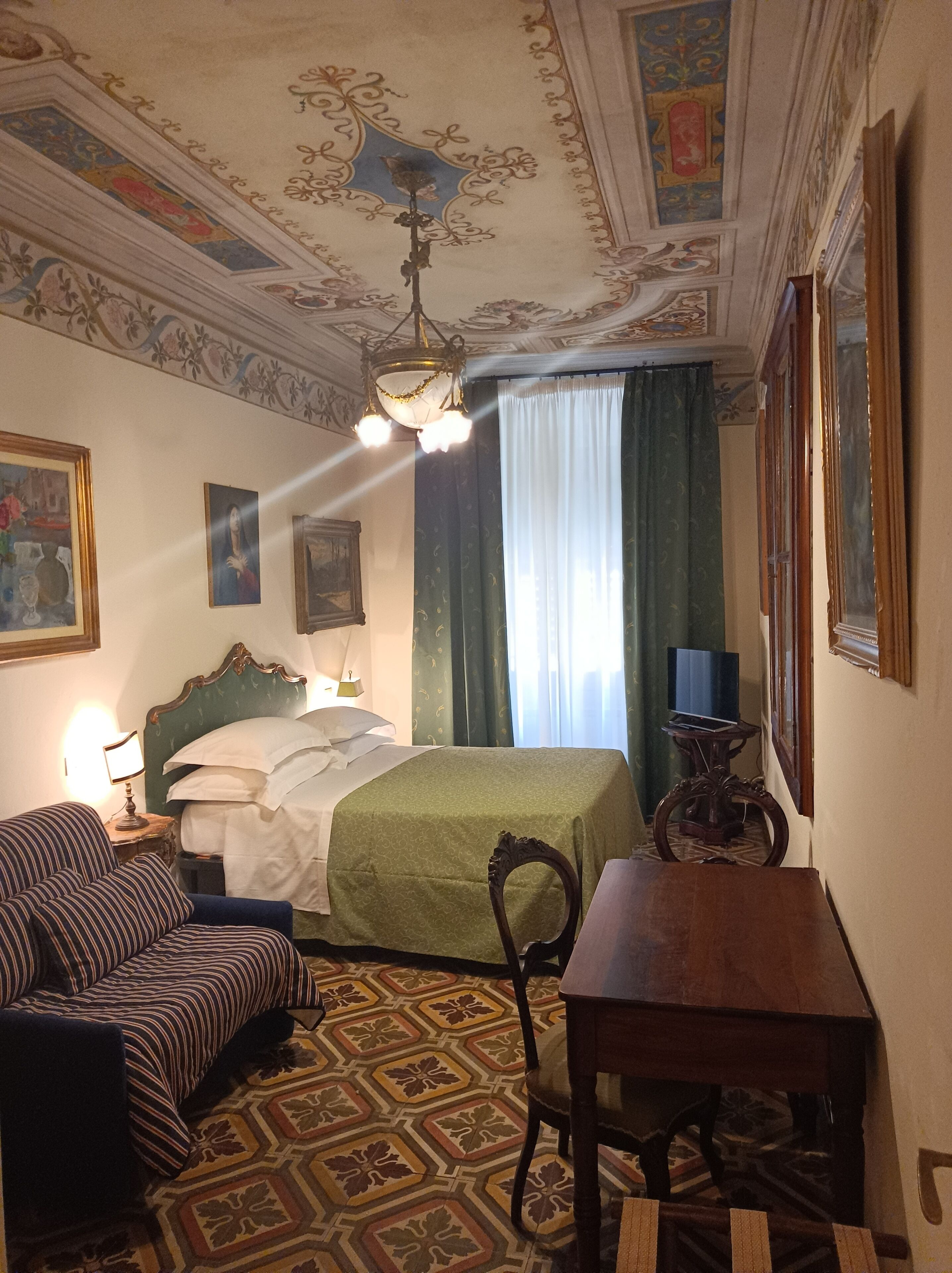 Ein Hotelzimmer mit Bett, Stuhl, Tisch und Fernseher.