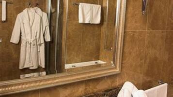 Un baño con un espejo grande, un lavabo y un perchero para toallas.