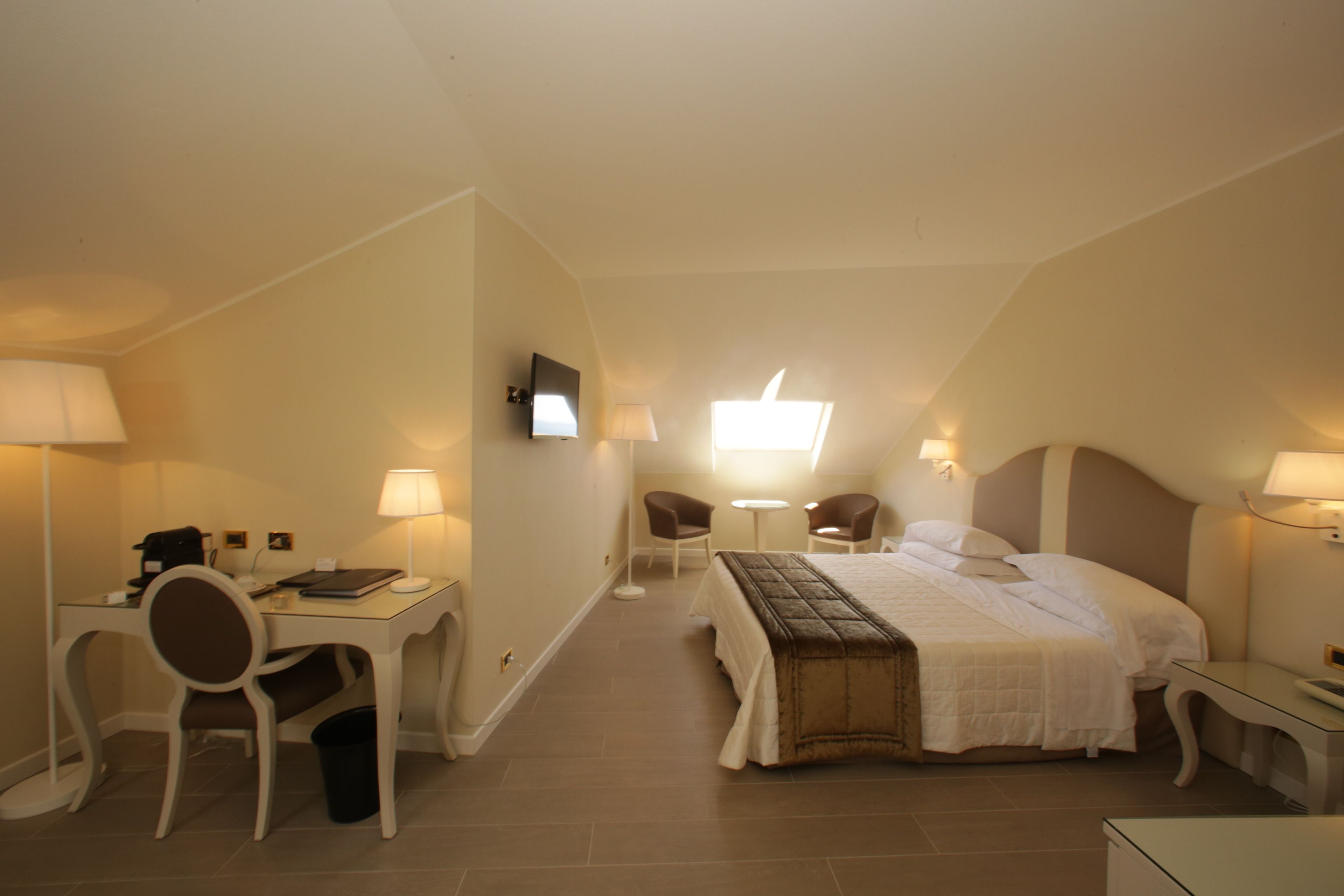 Una habitación de hotel con cama, escritorio, sillas y televisor.