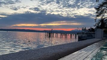 A swimming pool with a view of a sunset over water and a pier.
