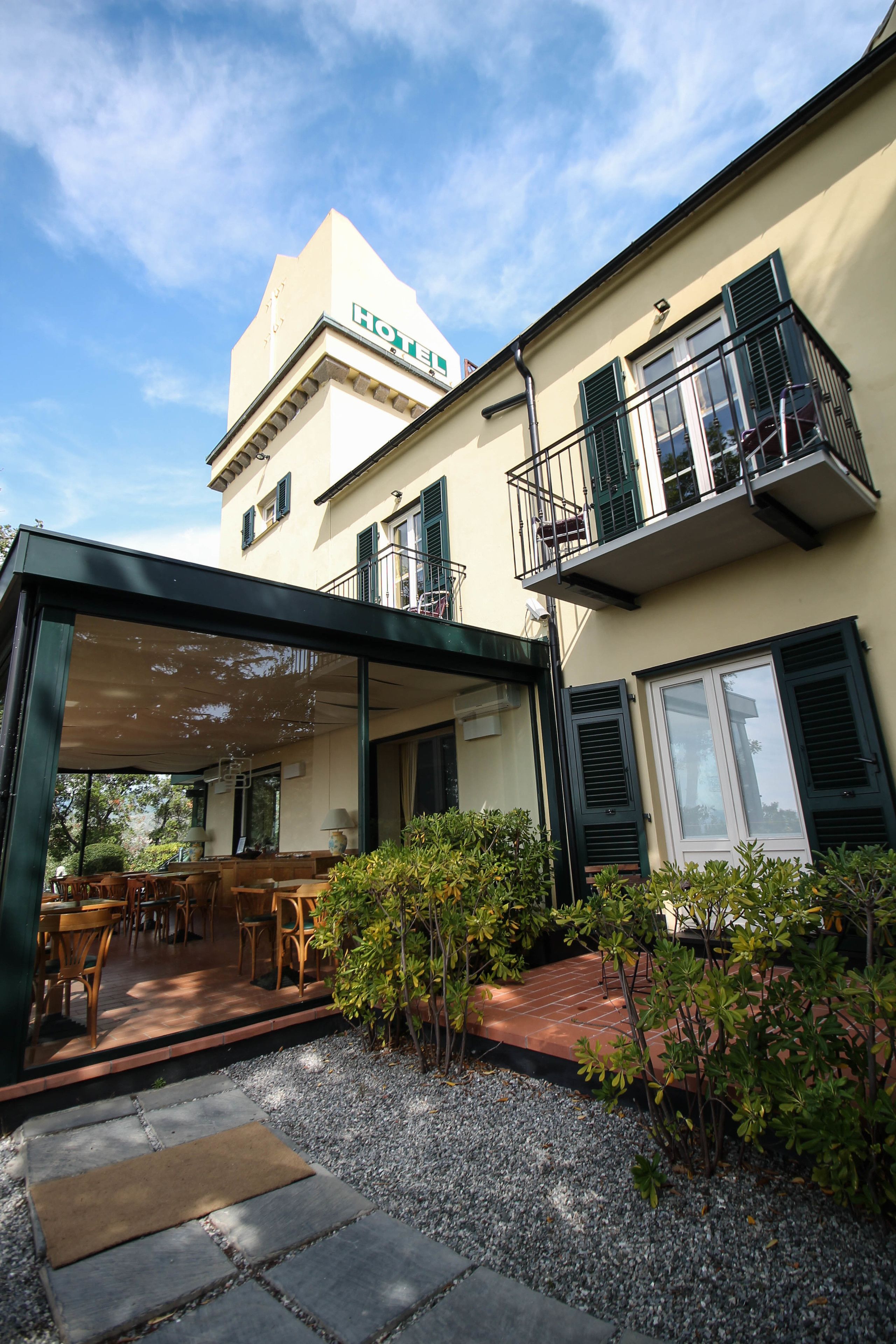 Un hôtel doté d’un espace extérieur aménagé et couvert, d’un jardin avec du gravier et des plantes, et d’un bâtiment avec un balcon.