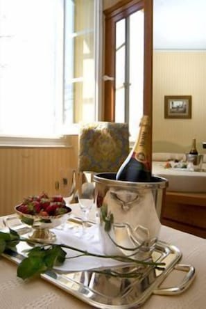 A table with a champagne bottle, a bowl of strawberries, and a vase with a flower. - Relais San Rocco (Casarza Ligure)