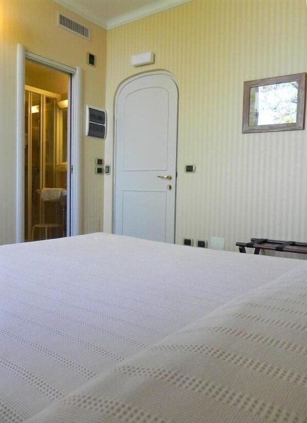 A hotel room with a large bed, a door, and a window. - Relais San Rocco (Casarza Ligure)