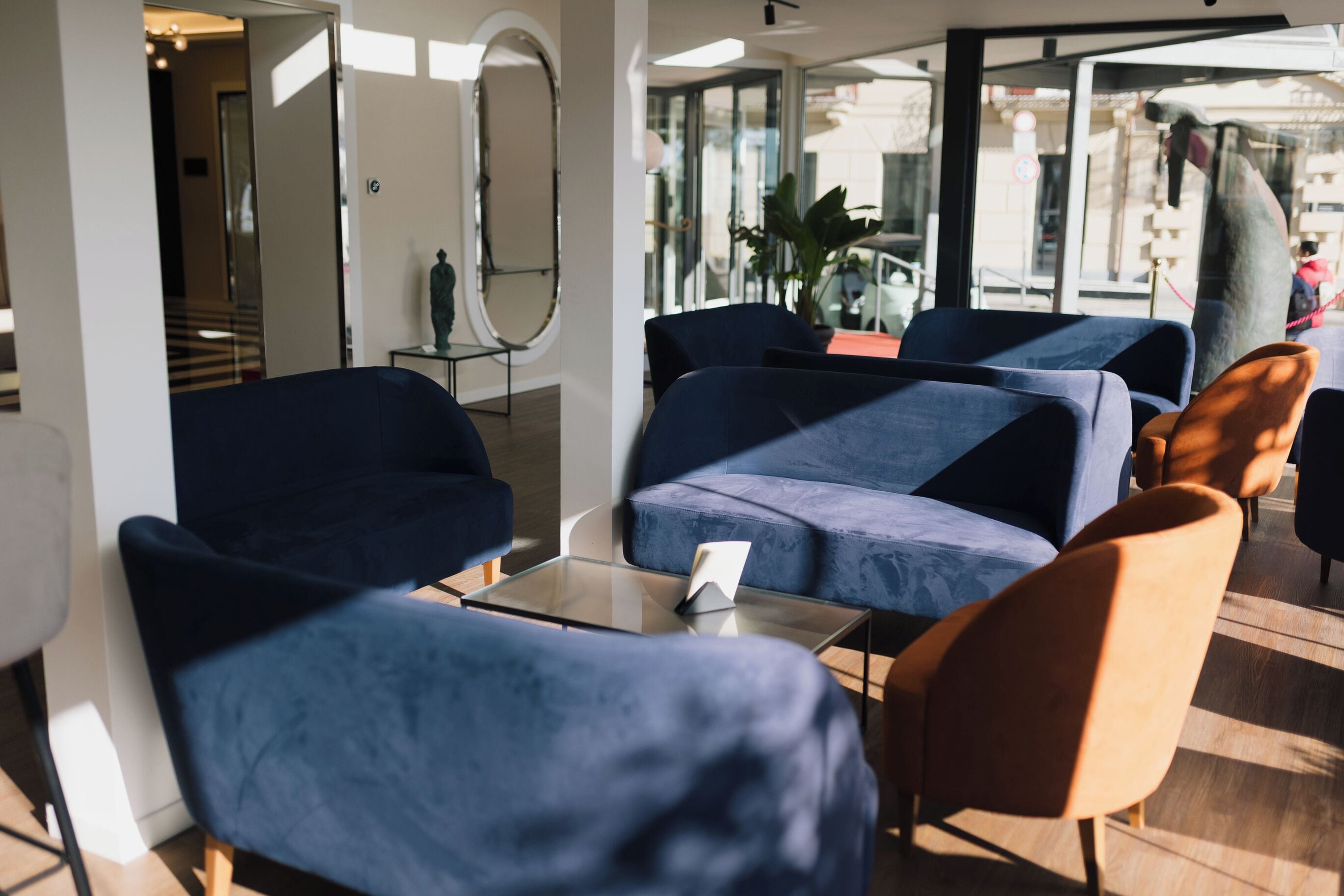 A modern lobby with dark blue seating, a glass wall, and a visible staircase.