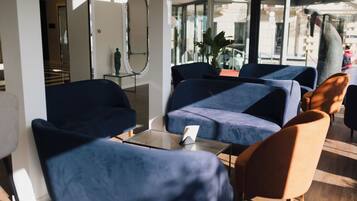 A modern lobby with dark blue seating, a glass wall, and a visible staircase.