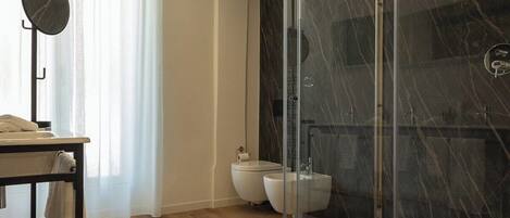 Un baño moderno con cabina de ducha de vidrio, inodoro y bidé.