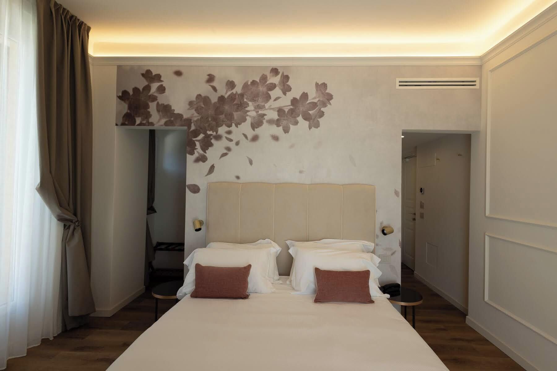 Une chambre d’hôtel avec un grand lit, deux tables de chevet, une armoire et un espace douche.