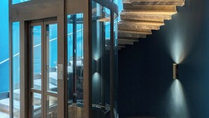 A modern elevator with glass doors and a metal exterior, leading to a staircase with a dark finish and a handrail. - SPLENDIDE RIVIERA   (Rapallo)