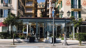 A hotel entrance with a glass canopy, outdoor seating, and a pedestrian crossing. - SPLENDIDE RIVIERA   (Rapallo)