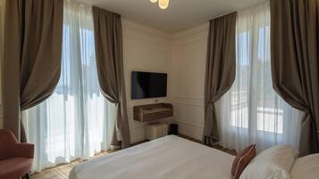A hotel room with a large bed, a TV mounted on the wall, and a wooden side table.