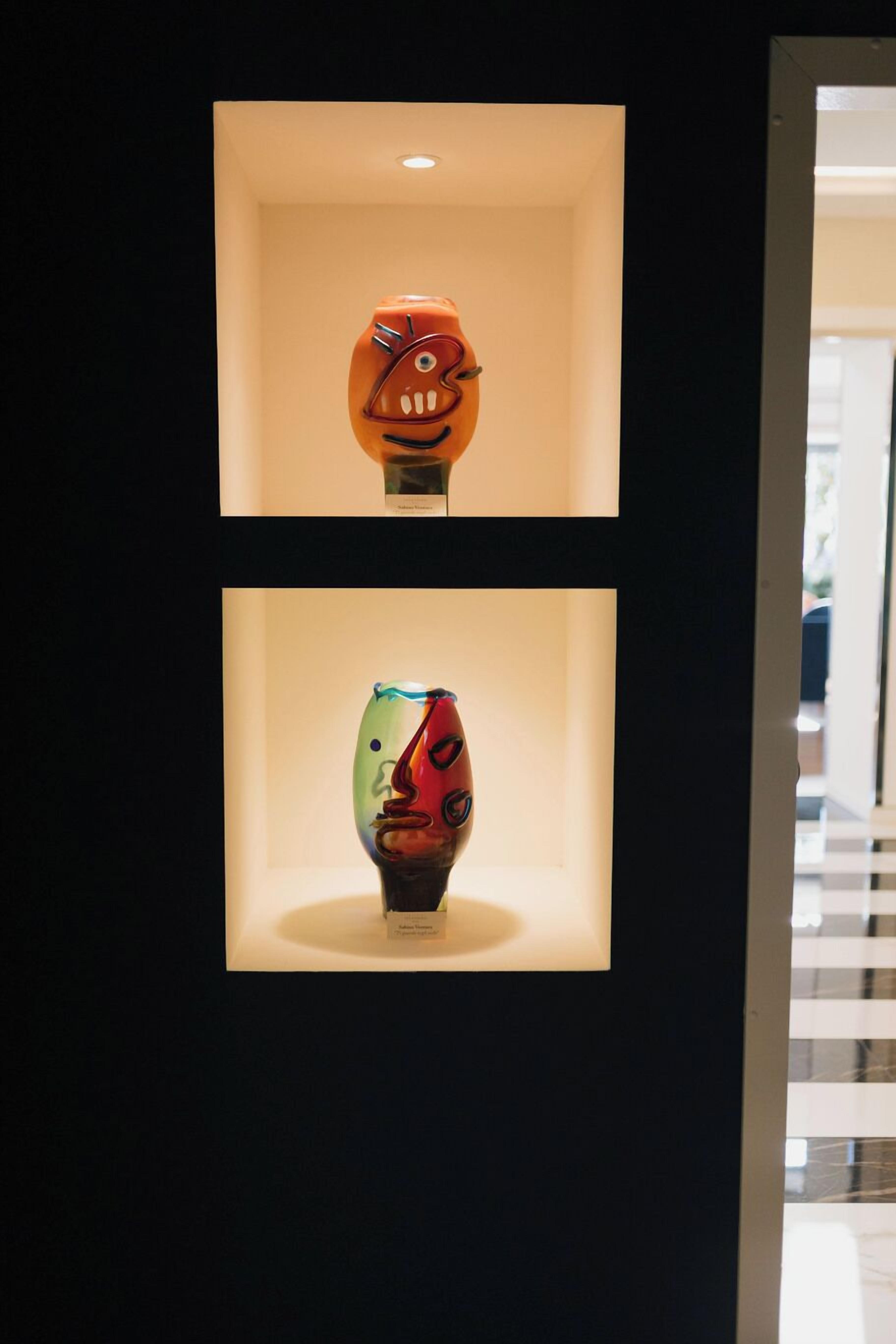 Two glass sculptures in illuminated display cases.