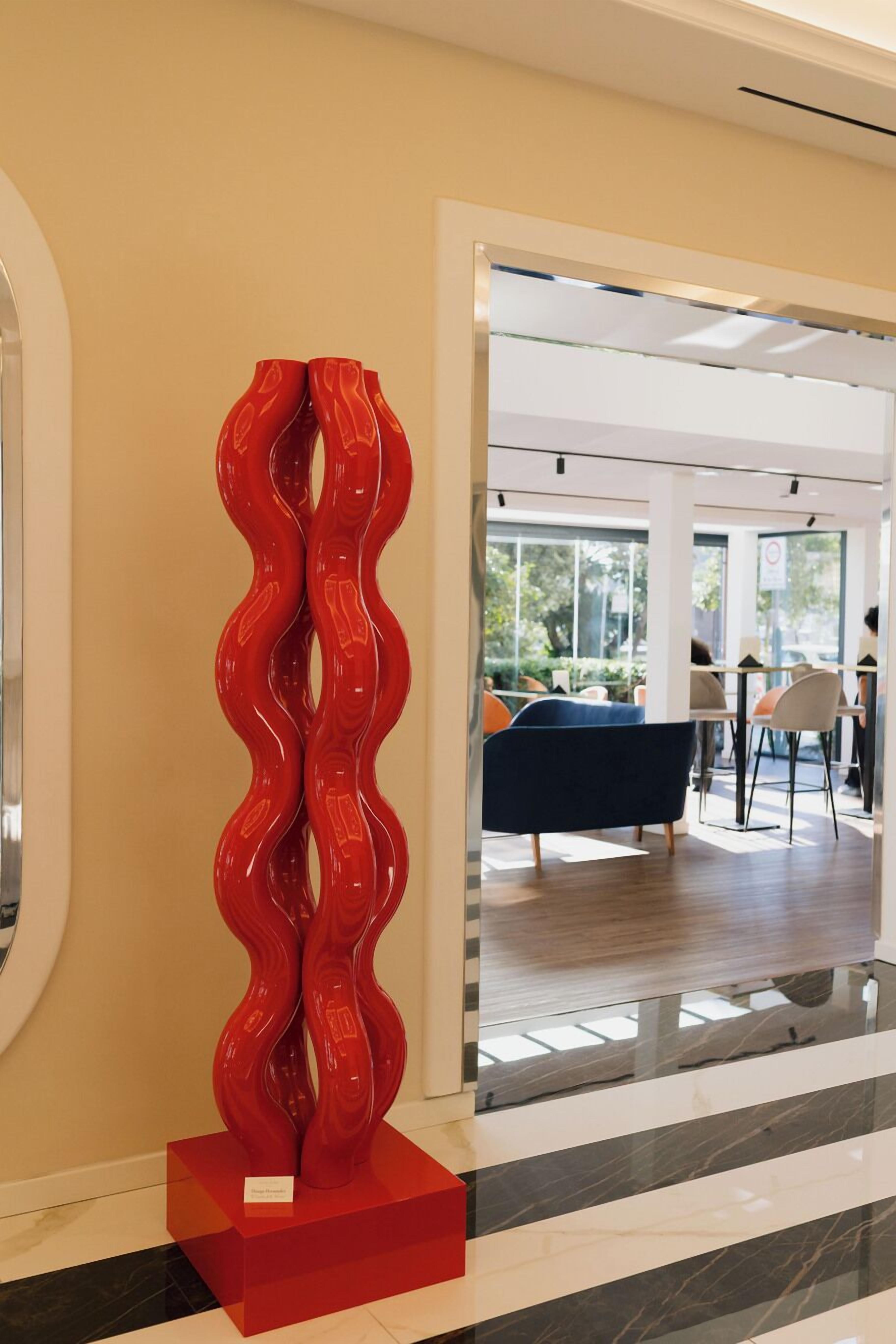 Un interior moderno con una escultura abstracta roja, una mesa de billar y una zona de estar.
