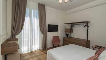 A hotel room with a bed, a desk, a chair, a television, and a wardrobe.