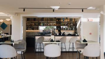 A modern bar area with a bar counter, stools, and a variety of bottles.