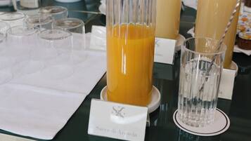 A buffet table with various food items and drinks, including orange juice and water.