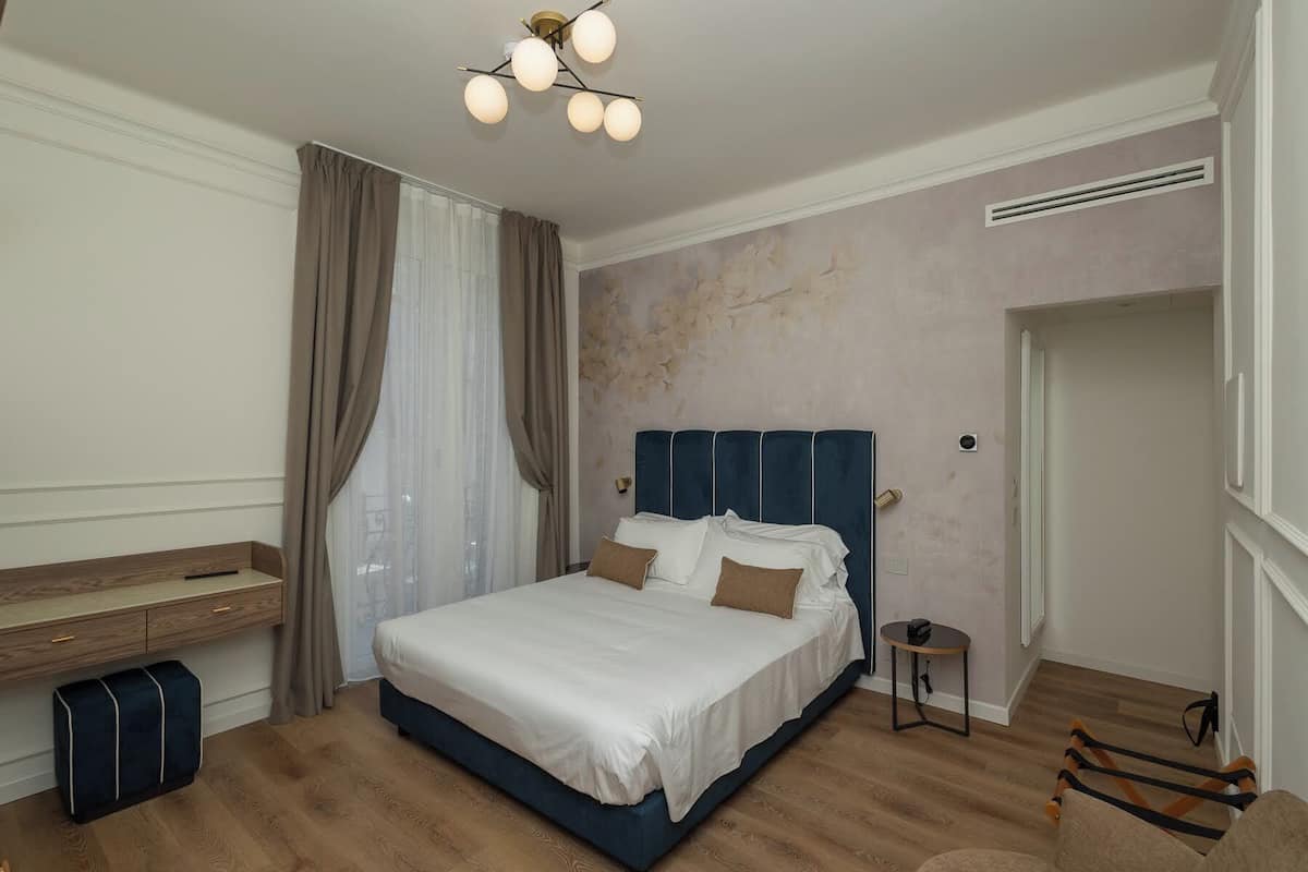 Ein Schlafzimmer mit einem Bett, einem Nachttisch, einem Sessel, einem kleinen Tisch und einer Deckenleuchte.