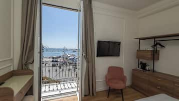 Una camera d'albergo con balcone, televisione, scrivania, sedia e armadio.
