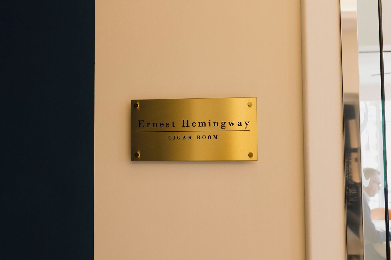 Una targa di ottone su una parete con la scritta 'Ernest Hemingway Cigar Room'.