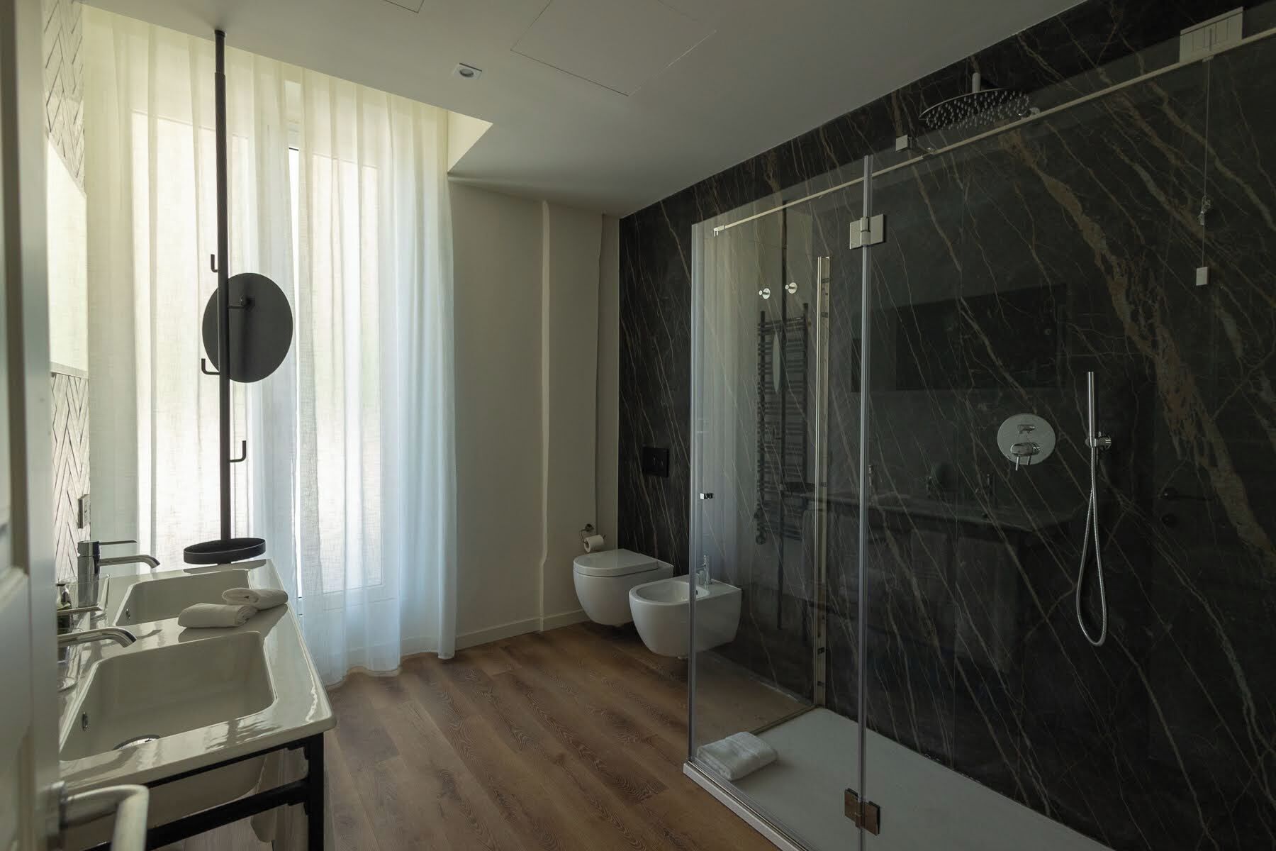 A modern bathroom with a glass shower enclosure, a toilet, and a sink with a towel.