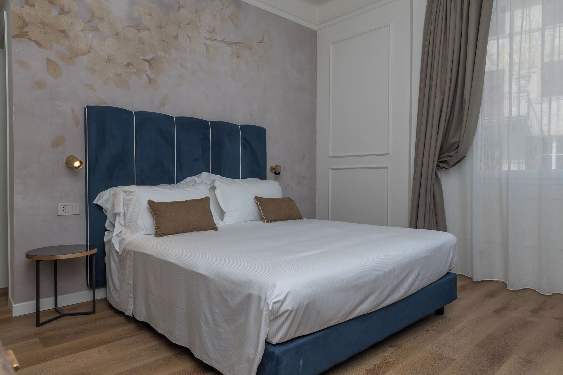 Ein Schlafzimmer mit einem großen Bett, einem kleinen Nachttisch und einer Wand mit einem Blumenmuster.