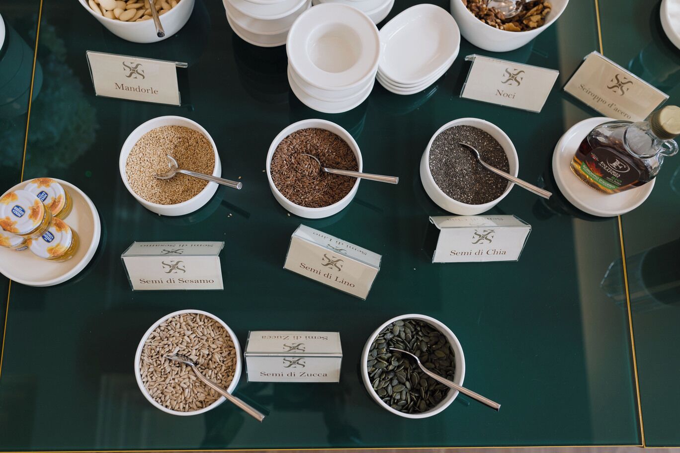 A variety of nuts and seeds displayed in bowls with labels, arranged on a table.