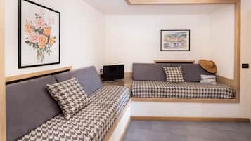 A modern bedroom with two beds, a television, and artwork on the walls.