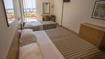 A hotel room with two beds, a desk, a chair, a dresser, and a large window offering a view of the marina.