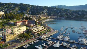 A marina with numerous boats docked, surrounded by a coastal town with buildings and a hilly backdrop. - Hotel Laurin (Santa Margherita Ligure)