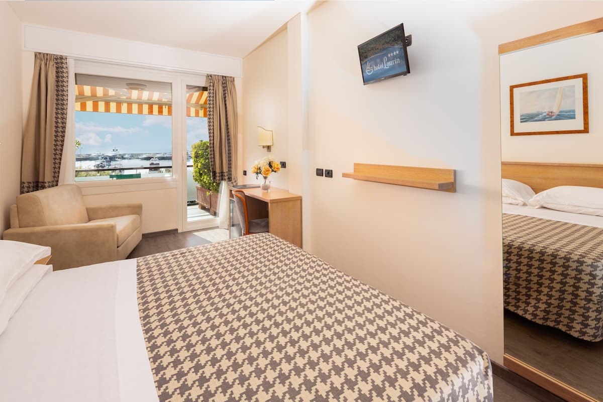 Une chambre d’hôtel avec un grand lit, un bureau, une chaise et un téléviseur fixé au mur.