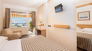 Una habitación de hotel con una cama grande, un escritorio, una silla y un televisor en la pared.