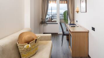 Ein gemütlicher Raum mit einer Couch, einem kleinen Schreibtisch und Blick auf eine Marina durch das Fenster.