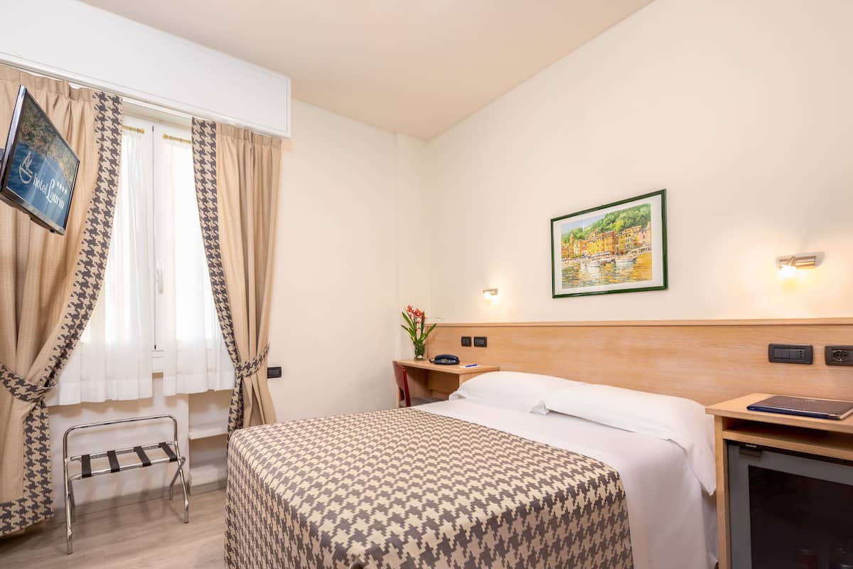 Une chambre d’hôtel avec un lit, un bureau, une chaise, une télévision et un tableau au mur.