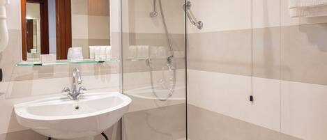 A modern bathroom with a glass-enclosed shower, a white sink, and a toilet.