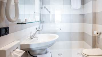 A modern bathroom with a large sink, mirror, shower, and toilet.